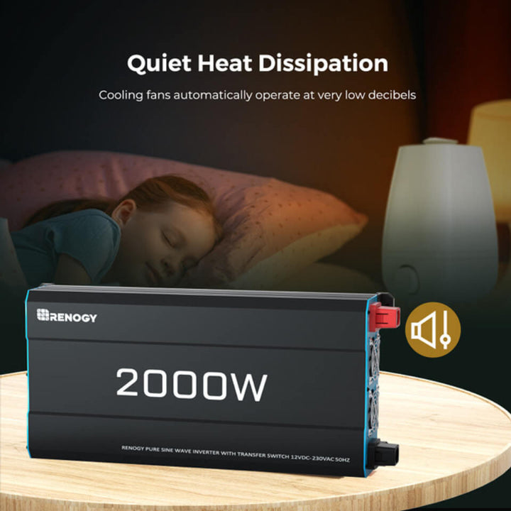 The 2000W Renogy inverter sits on a wooden table in a softly lit room. In the background, a child sleeps peacefully beside a lamp, emphasizing the inverter’s quiet fan operation.