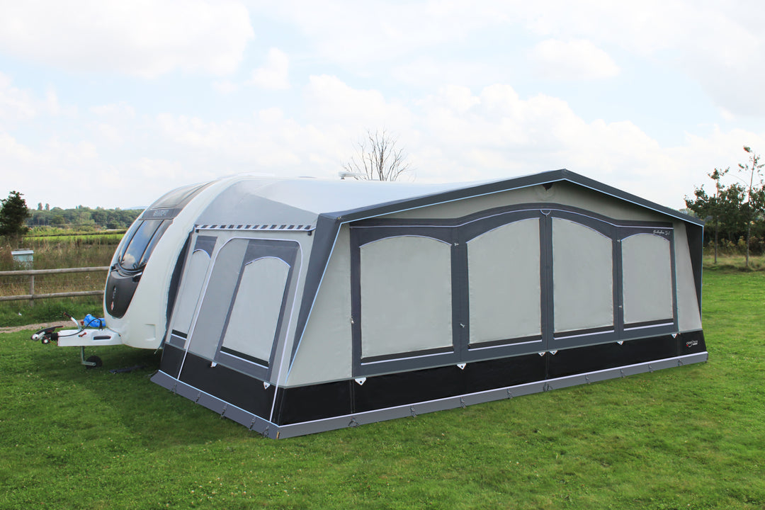 A Camptech Buckingham DL awning connected to a caravan in a field shown from the front left