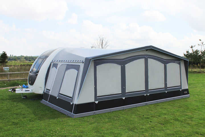 A Camptech Buckingham DL awning connected to a caravan in a field shown from the front left
