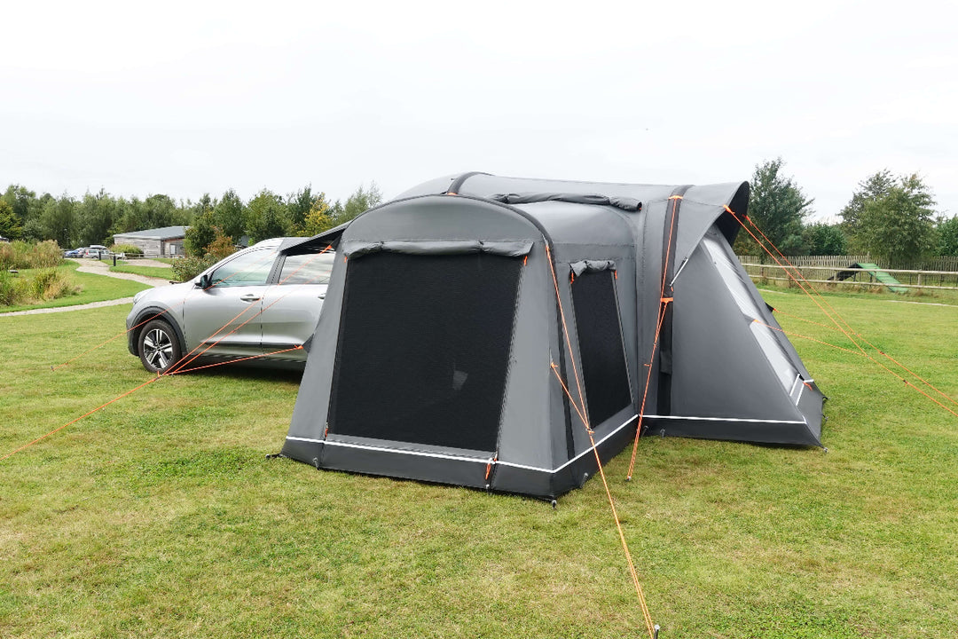 Camptech Adelaide rear car tent fitted to a vehicle, showing mesh ventilation panels and extended roof awning on open green camping ground.