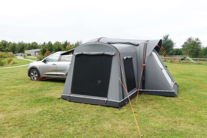 Camptech Adelaide rear car tent fitted to a vehicle, showing mesh ventilation panels and extended roof awning on open green camping ground.