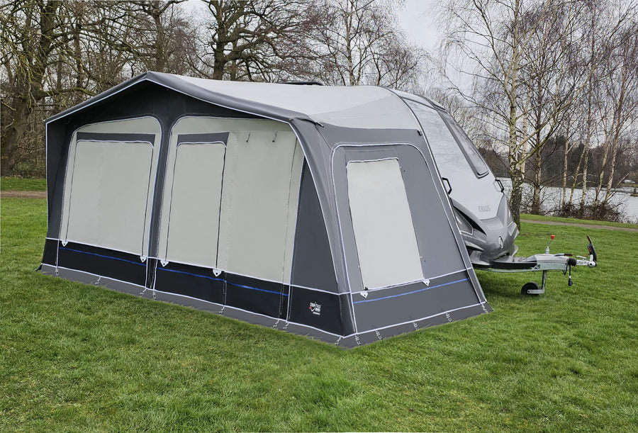 Camptech Archduke full caravan awning fitted to a Knaus Sport & Fun caravan, featuring grey panels with zipped covers on a green campsite beside trees.
