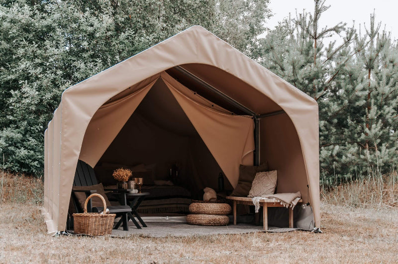 FDomes Glamping Tent with open entrance and rustic furniture – featuring interior furnishings like a bench, black chair, side tables, and a bed partially visible inside, on a natural background.