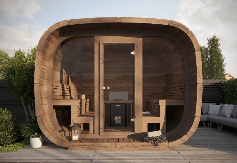 Front view of the InMedias Cubus Premium Outdoor Sauna with benches inside and a glass door in the center, showcasing the interior heater,  on a natural outdoor background.