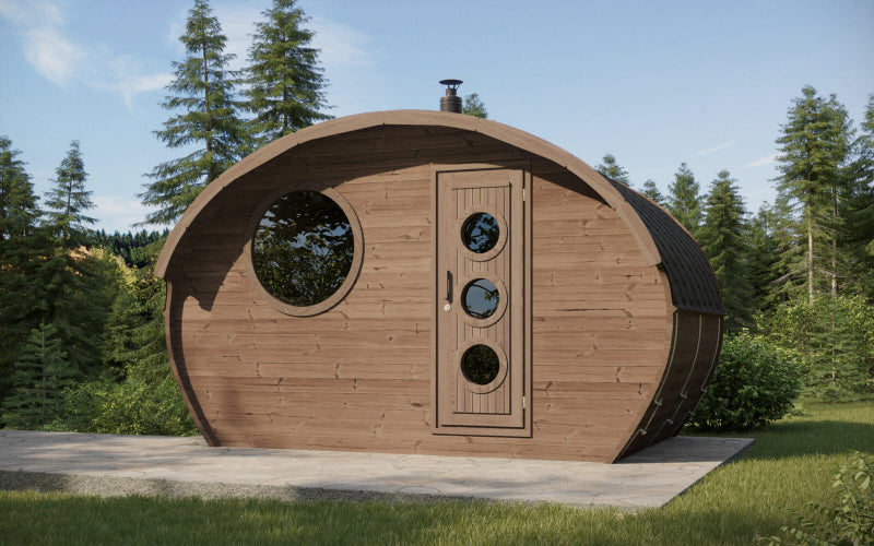 Outdoor photo of the InMedias Oval Sauna Frodo 240 in a forest clearing, featuring dark stained wood, circular window, and circular-accented door , natural forest background with trees and grass.