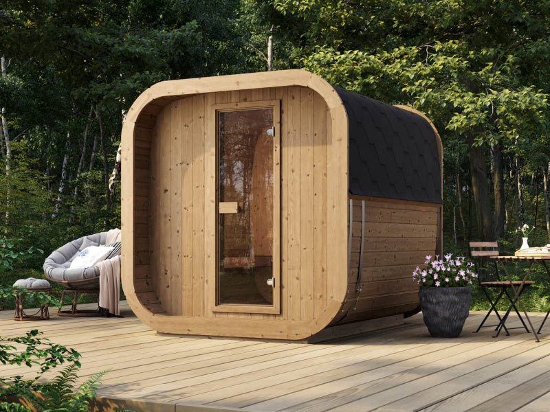 InMedias Sauna Icon 200S placed on an outdoor deck, surrounded by forest greenery, black roof, and glass door entrance.