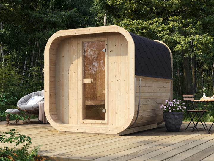 InMedias Sauna Icon 200S on a wooden deck surrounded by lush forest, featuring light natural wood and a glass door.