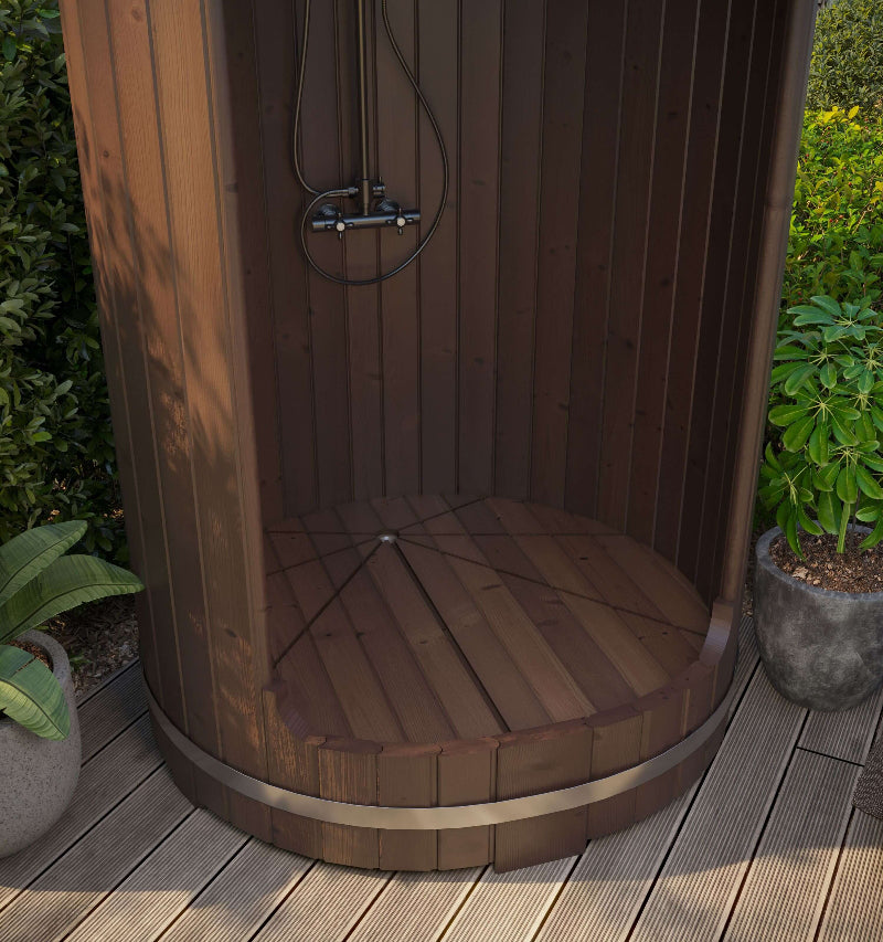 Outdoor view of InMedias Shower Barrel installed on wooden decking – partially shaded, surrounded by potted plants, on a garden background.