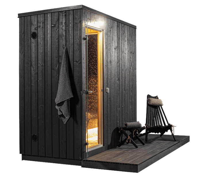 KUUT 4-person steam sauna with a black wooden exterior, open glass door revealing mosaic-tiled interior, and two wooden lounge chairs on the deck, on a transparent background.