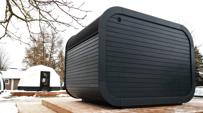 Rear side of Viking Industrier Luna Outdoor Sauna 3.3 x 2.4m, matte black cladding, snowy outdoor setting.