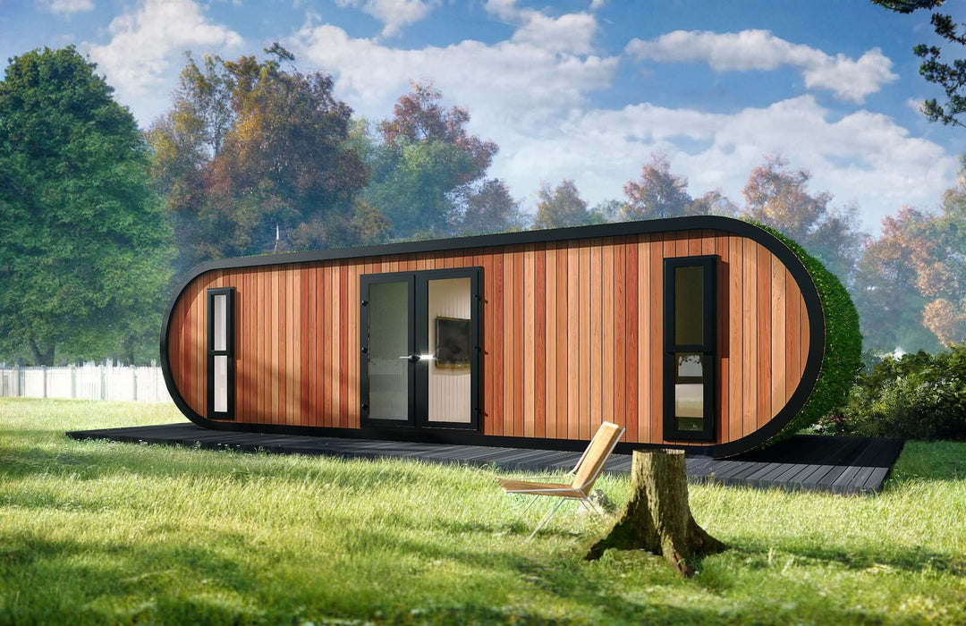 Modern glamping pod with wood cladding and black-trimmed double doors, placed on a grassy lawn with trees and a chair on the side.