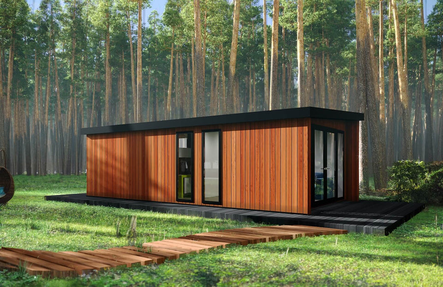 Modern glamping cabin with timber cladding and black-framed glass doors, set on a raised deck with wooden path in a tall pine forest.