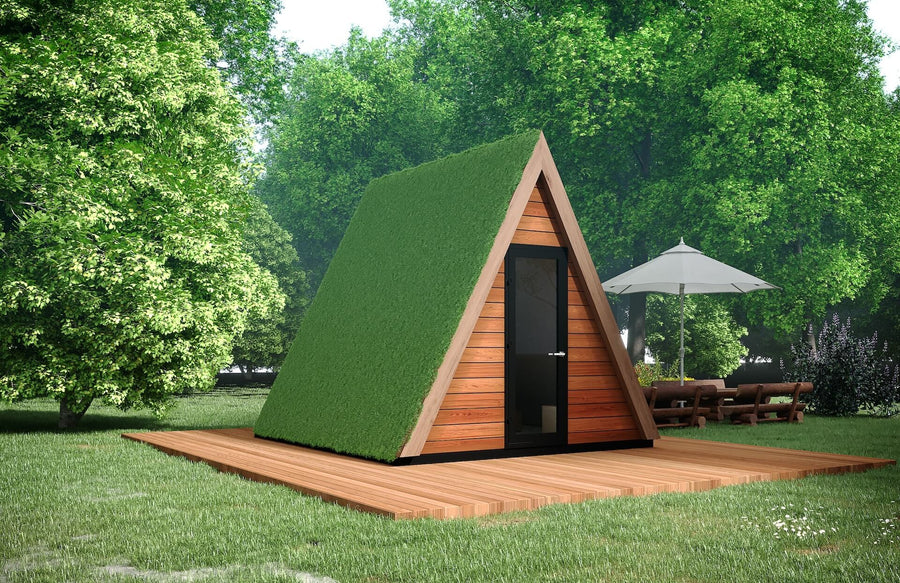 A-frame glamping pod with wooden siding and grass-covered roof on a timber deck, surrounded by green trees in a forested setting.