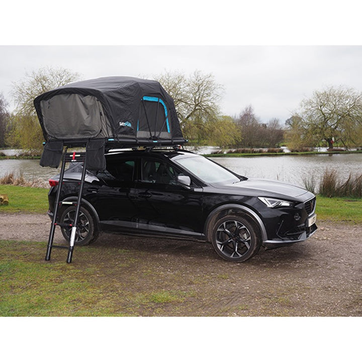 Black car fitted with Skypod Lite rooftop tent featuring blue trim and ladder access.