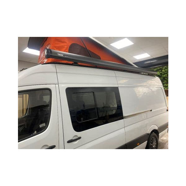A black Thule Awning attached to a white Sprinter Van