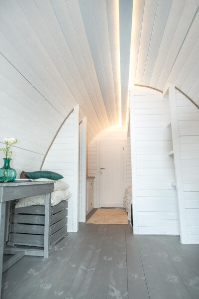 Viking Industrier 3.2 x 5.9m Camping Pod hallway view with curved ceiling lights and doorway, white interior on a wood background.