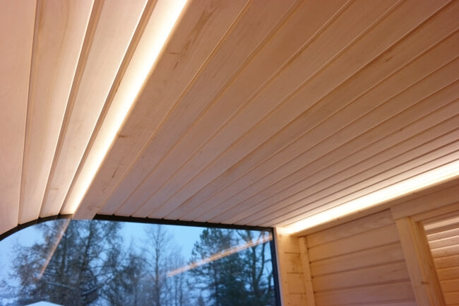 Ceiling with LED strip lighting in Viking Industrier Luna Outdoor Sauna 3.3 x 2.4m, showing snow outside the window.