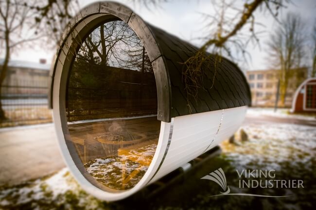 Rear angle of a Viking Industrier Barrel Sauna 2.2 x 3m showing a large round tinted glass wall, outdoors with a snowy ground.
