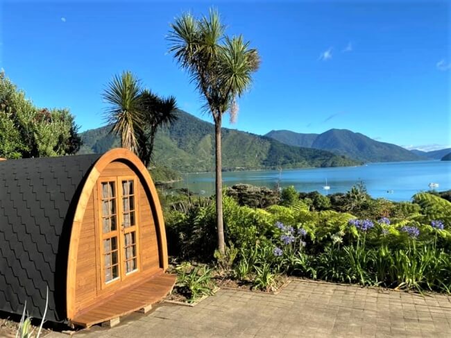 Viking Industrier 2.4 x 3.5m camping pod placed on a stone path overlooking a lake and mountain landscape on a clear sunny day.