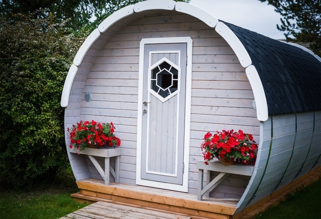 Front exterior of the Viking Industrier Ice-Viking Sleeping Barrel 3 x 4.8m with a white-trimmed door and two flower boxes.