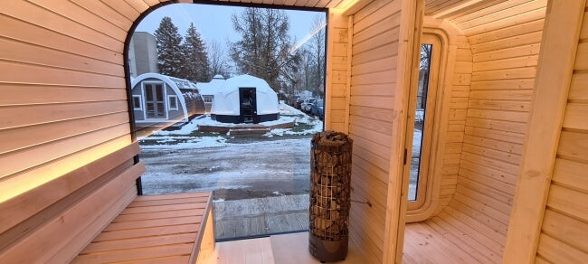Interior view of Viking Industrier Luna Outdoor Sauna 3.3 x 2.4m with a large glass wall and visible snow outside.