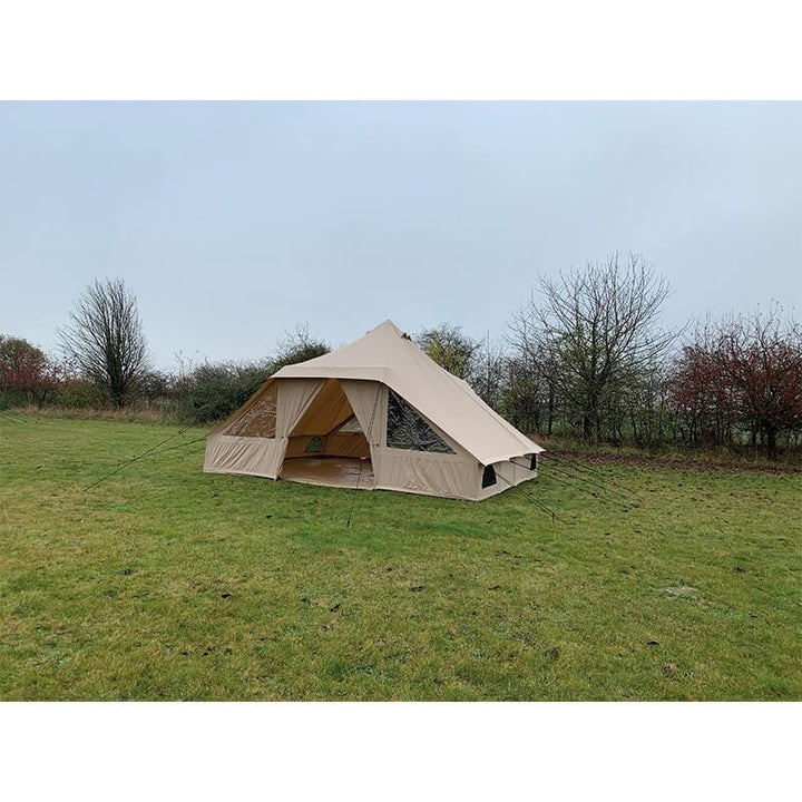 Angled view of the Quest Leisure Signature Touareg bell tent on a grassy field with autumn trees in the distance.