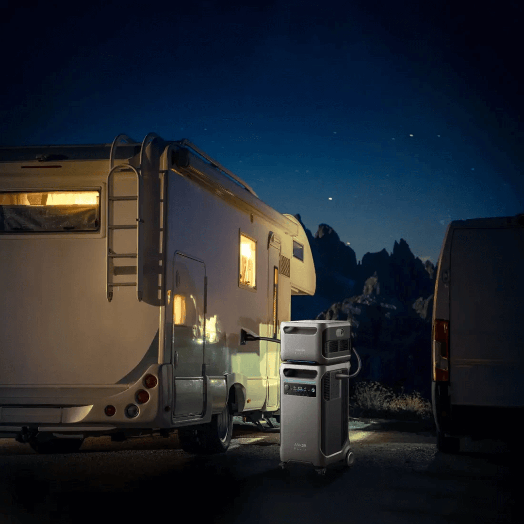 Anker portable power station connected to RV under starry night sky, in an outdoor campsite setting.