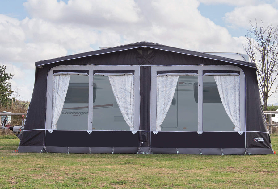 Camptech Hampton DL full caravan awning with white curtains, attached to a Swift Challenger caravan on green grass under a cloudy sky.