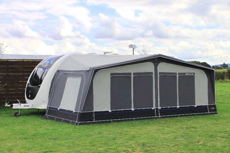 Camptech Savanna DL caravan awning with window panels closed, attached to a modern white caravan on grassy ground under a bright sky.