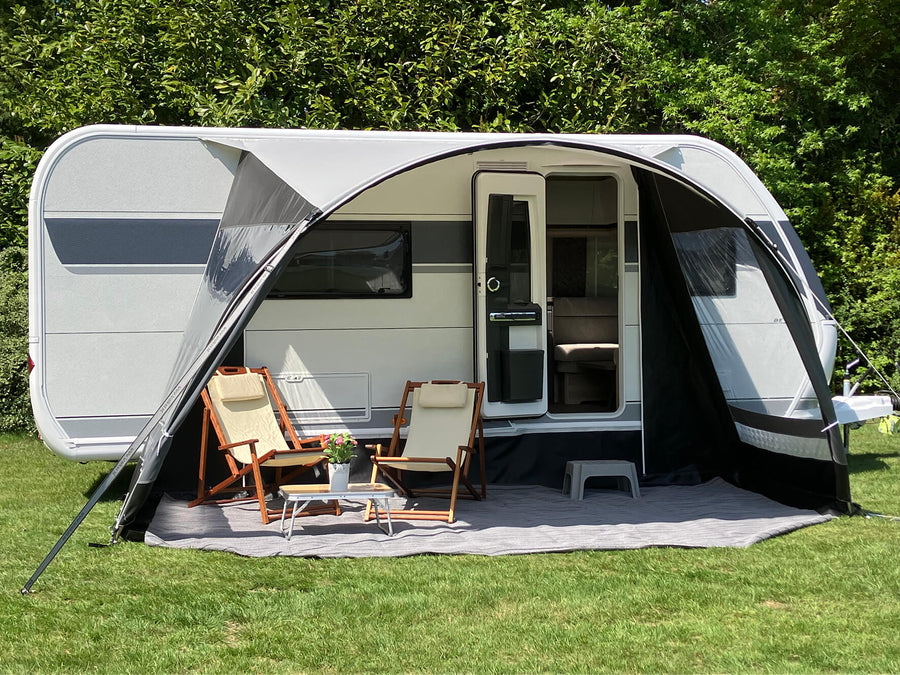 Walker Combi-Luxe awning setup on caravan with outdoor seating and coffee table on a grassy campsite.