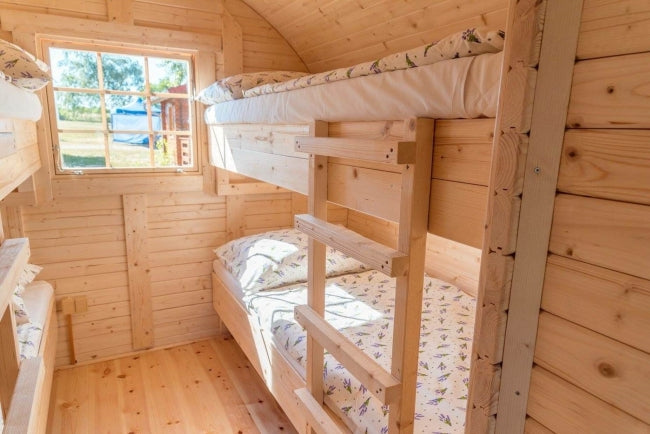 Bunk bed setup inside the Viking Industrier Ice-Viking Sleeping Barrel 3 x 4.8m with wooden walls and floral bedding.