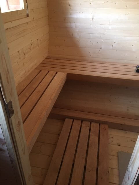 Interior of InMedias Oval Sauna with light natural wood benches and flooring.