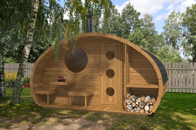 Exterior shot of InMedias Oval Sauna Frodo 300, installed under trees with log storage and soda bottles , on a garden background with dappled sunlight.