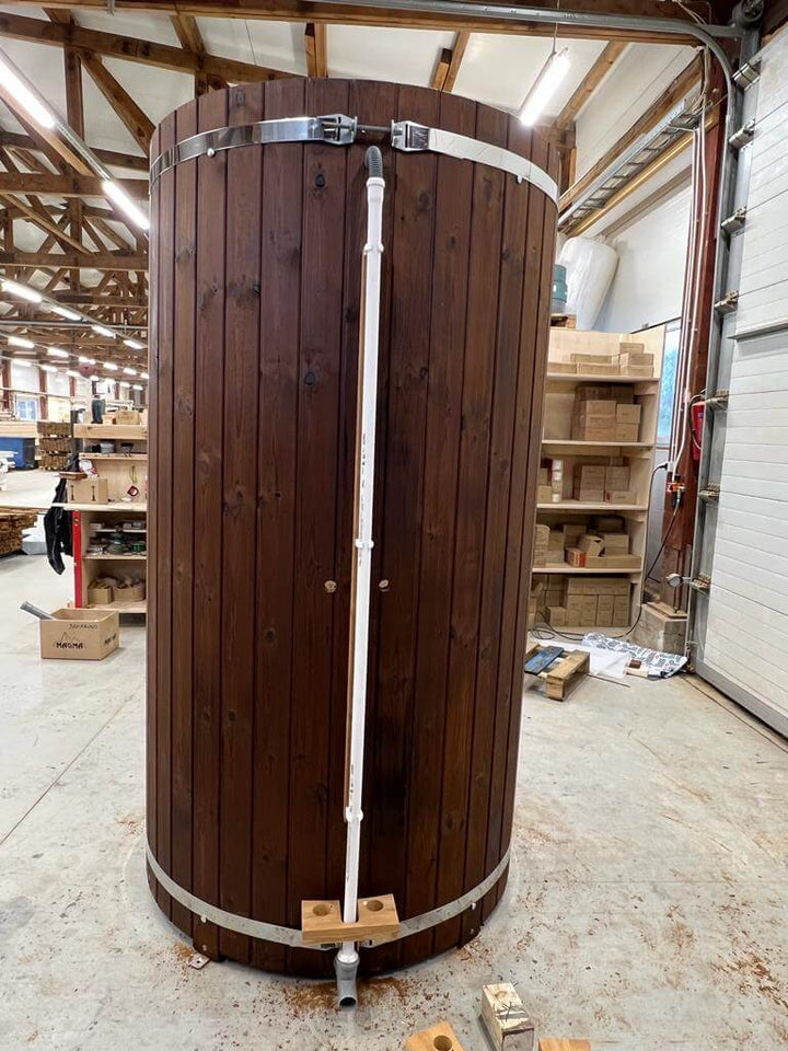 Back view of InMedias Shower Barrel with visible plumbing setup – dark wood paneling with a mounted white water pipe.