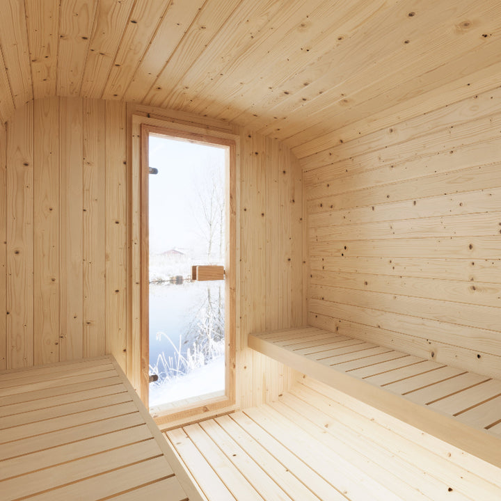 Interior view of the InMedias Sauna Icon 250S showing bright wooden walls and benches with a frosted glass door facing snowy outdoors.
