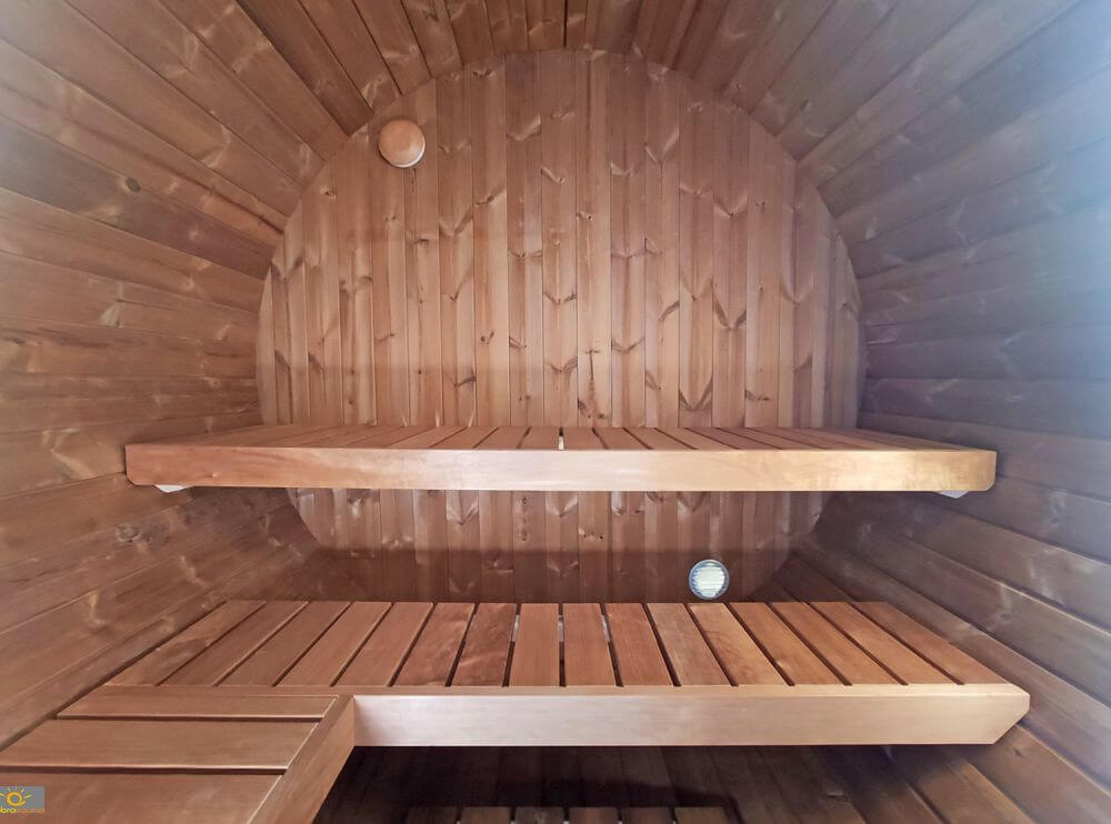 Interior view of InMedias Terrace Sauna showing two-tiered wooden benching in a circular barrel design with warm brown wood panels.