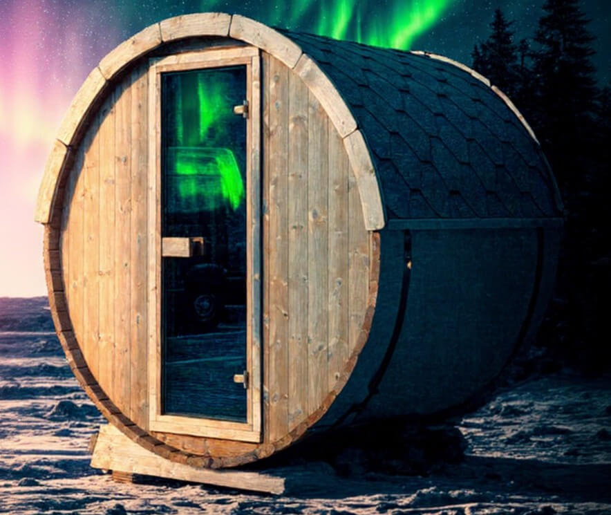 InMedias Terrace Sauna with natural wood finish standing in snowy terrain under a vibrant aurora borealis night sky.