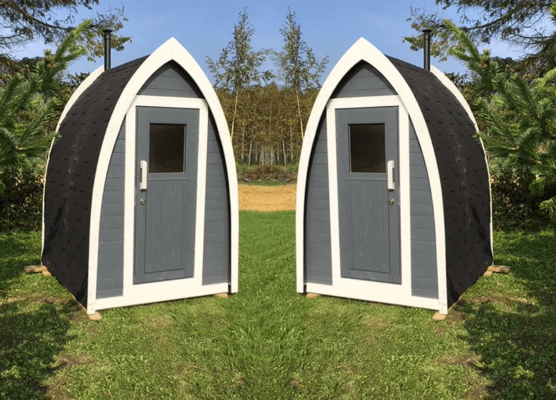 InMedias Toilet Barrel twin units with gray-and-white painted wood finish, placed symmetrically on green lawn under blue sky – outdoor grassy background.