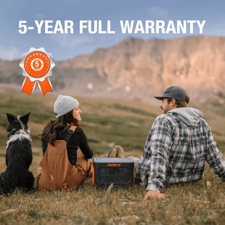Couple relaxing on a grassy hillside with their dog and Jackery Explorer 1000 Pro, mountains in the background.