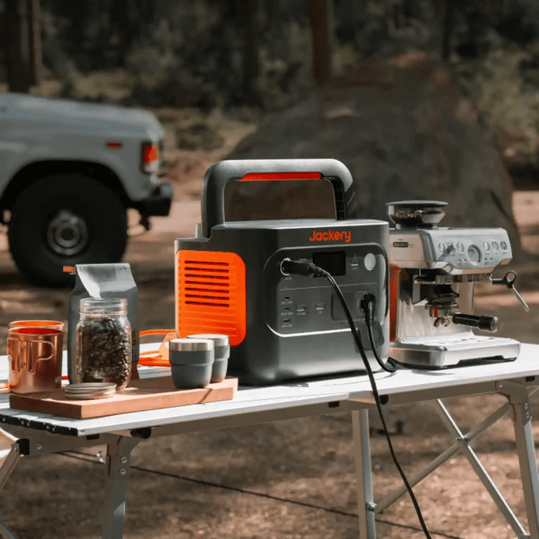 Jackery Explorer 1000 V2 powering coffee machine on a camping table in the forest.