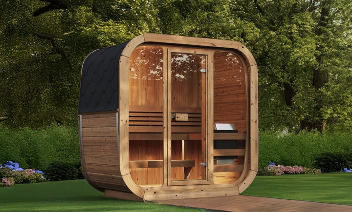 InMedias Sauna Icon 125 angled view – a modern, cuboid-shaped sauna made of natural wood with a glass front wall and black shingle roof, set on a lawn with trees in the background ,  outdoor garden background.