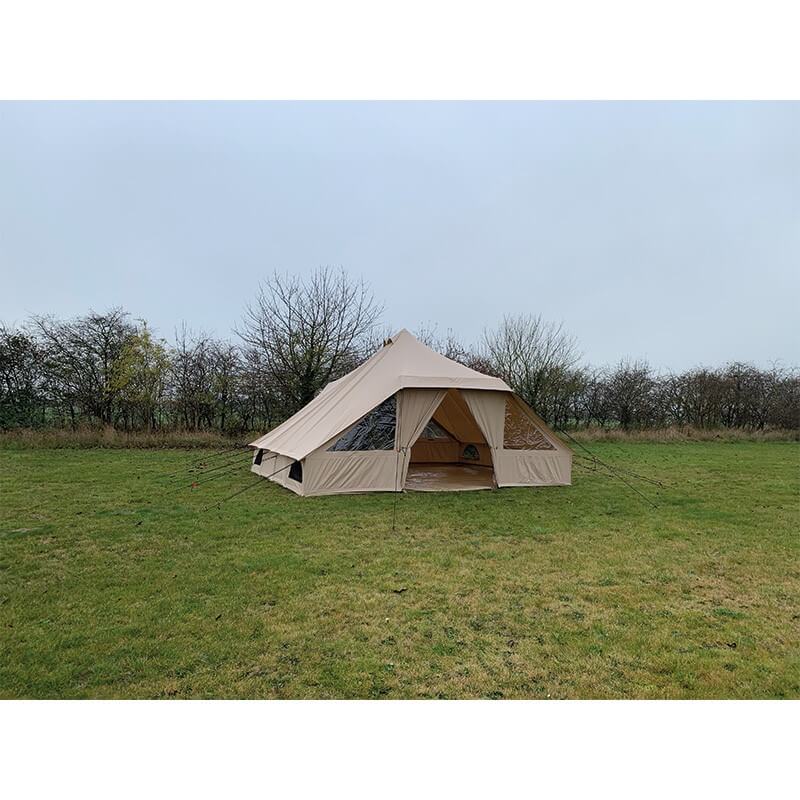 Side view of the Quest Leisure Signature Touareg bell tent set up on a grassy field with trees and a cloudy sky.