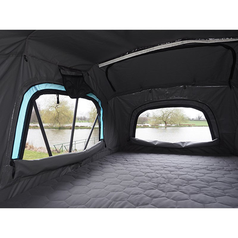 Interior of Skypod Lite rooftop tent showing spacious sleeping area and mesh windows overlooking a lake.