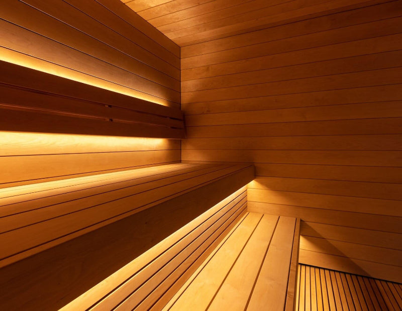 View of the Saunum AirCube Terrace sauna interior corner, displaying layered wooden bench seating with soft, indirect lighting.