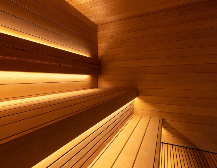 View of the Saunum AirCube Terrace sauna interior corner, displaying layered wooden bench seating with soft, indirect lighting.