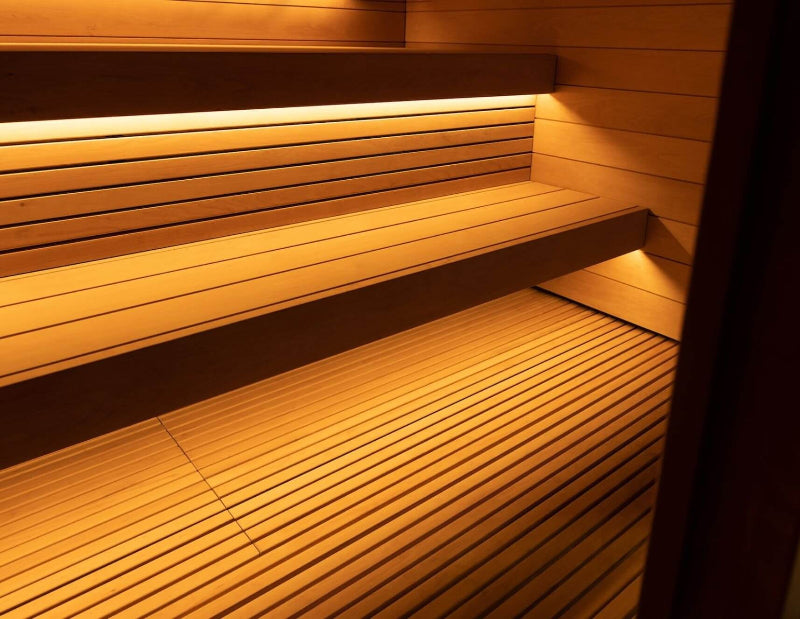 Interior close-up of the Saunum AirCube Terrace sauna showing slatted wooden flooring and tiered benches with integrated LED lighting.