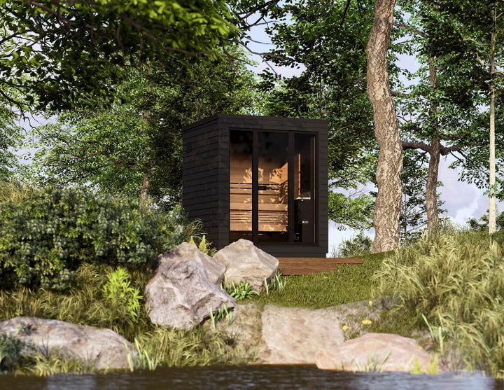 Saunum Classic Mini sauna in a forest setting near a river, surrounded by rocks and trees