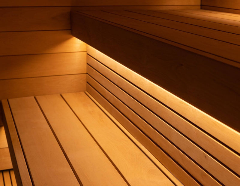 Detailed view of wooden sauna bench design inside the Saunum AirCube Space, highlighting integrated under-bench LED lighting and smooth plank finish.
