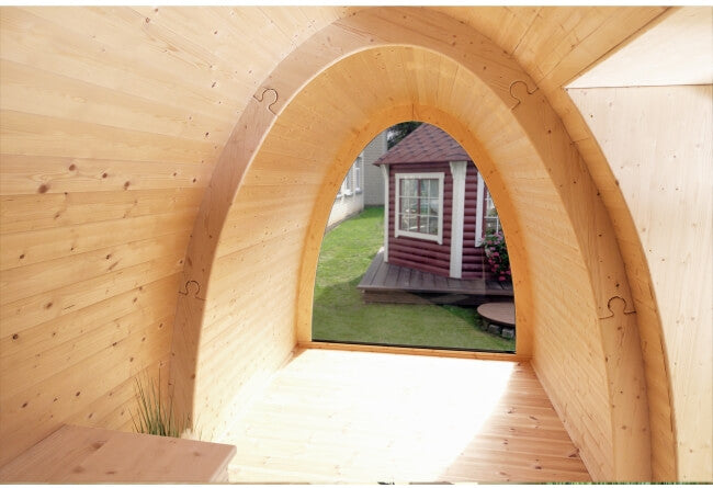 Interior view of the Viking Industrier 2.4 x 5.9m Camping Pod with arched natural wood walls and glass window on a grassy outdoor background.