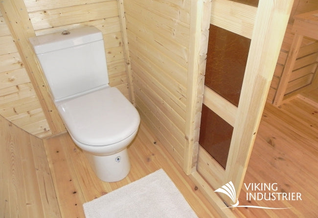 Toilet area of the Viking Industrier Ice-Viking Sleeping Barrel 3 x 4.8m featuring a standard white toilet and partial wooden partition.